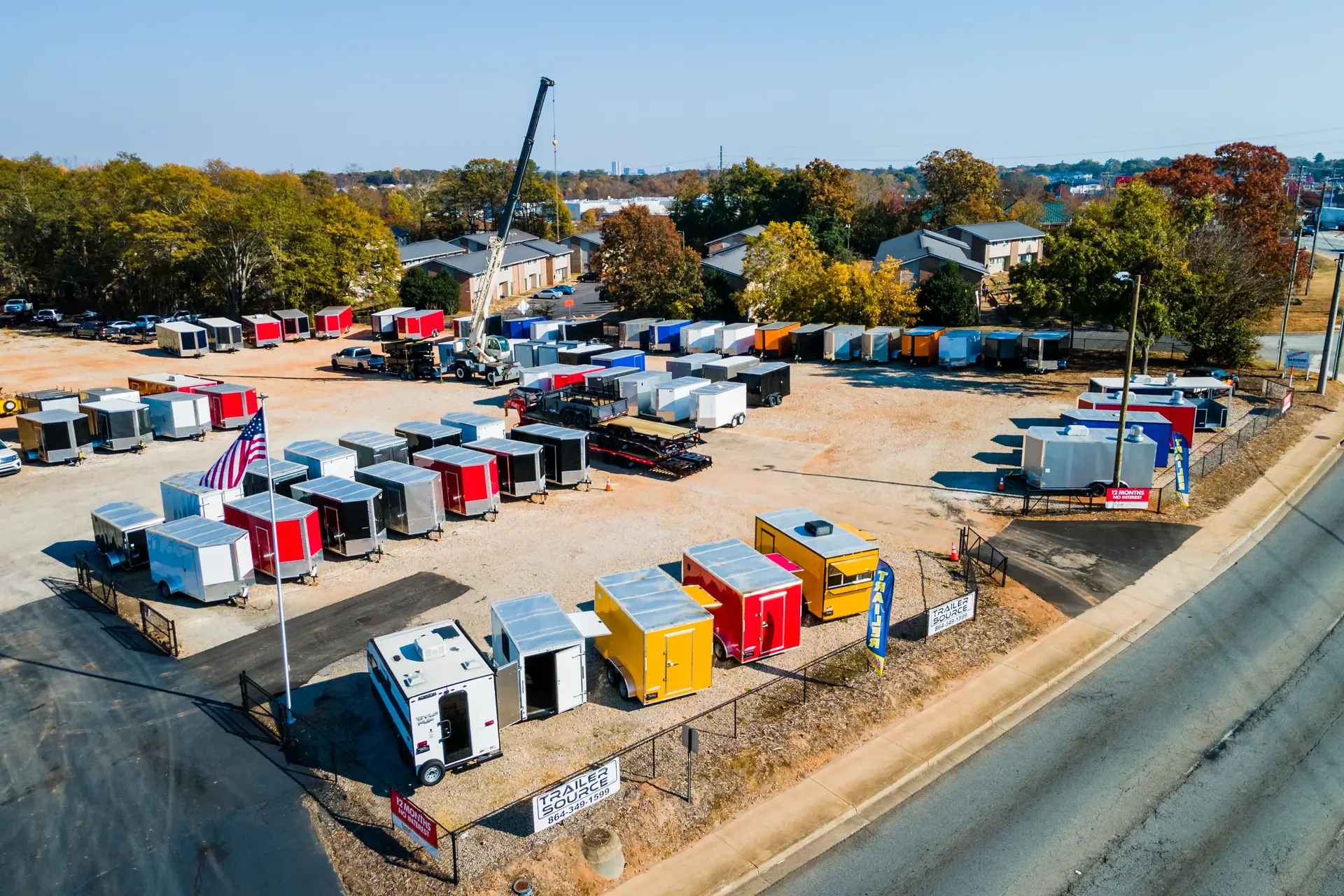 Aerial view of Trailer Source in Greenville, SC, with the Trailer Source sign, the flag and rows of enclosed and concession trailers